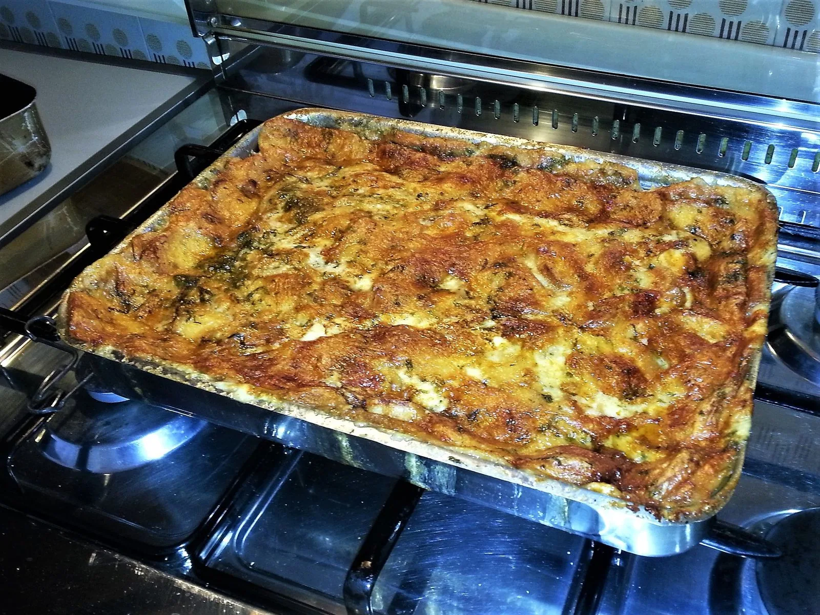 Teglia di zuppa gallurese appena sfornata, con la crosta dorata di pane e formaggio
